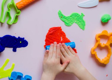 Çocuk elleri renkli kille oynuyor. Ev yapımı plastik. Kil kalıbı yapan kız. Ev yapımı kil. Çocuk oyun oynuyor ve oyun hamurundan yaratıyor. 