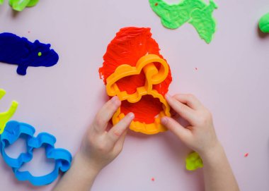 Çocuk elleri renkli kille oynuyor. Ev yapımı plastik. Kil kalıbı yapan kız. Ev yapımı kil. Çocuk oyun oynuyor ve oyun hamurundan yaratıyor. 