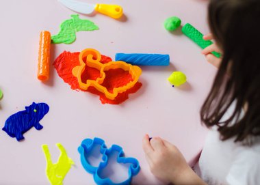 Çocuk elleri renkli kille oynuyor. Ev yapımı plastik. Kil kalıbı yapan kız. Ev yapımı kil. Çocuk oyun oynuyor ve oyun hamurundan yaratıyor. 