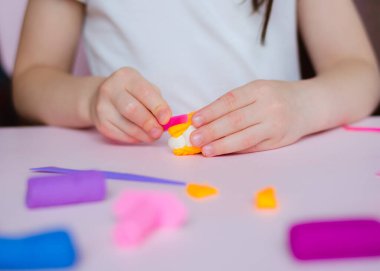 Çocuk elleri renkli kille oynuyor. Ev yapımı plastik. Kil kalıbı yapan kız. Ev yapımı kil. Çocuk oyun oynuyor ve oyun hamurundan yaratıyor. 