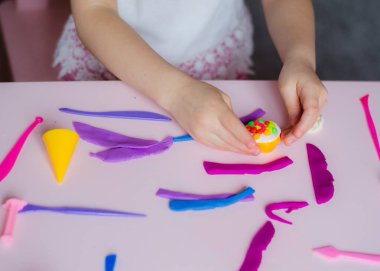 Çocuk elleri renkli kille oynuyor. Ev yapımı plastik. Kil kalıbı yapan kız. Ev yapımı kil. Çocuk oyun oynuyor ve oyun hamurundan yaratıyor. 