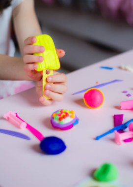 Çocuk elleri renkli kille oynuyor. Ev yapımı plastik. Kil kalıbı yapan kız. Ev yapımı kil. Çocuk oyun oynuyor ve oyun hamurundan yaratıyor. 