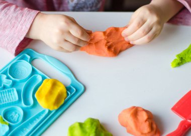 Renkli kil ile çocuğun el. Çocuk oyun ve oyun hamuru vagetables oluşturma. Modelleme kil kalıplama kız. Kil ev
