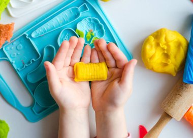 Renkli kil ile çocuğun el. Çocuk oyun ve oyun hamuru vagetables oluşturma. Modelleme kil kalıplama kız. Kil ev