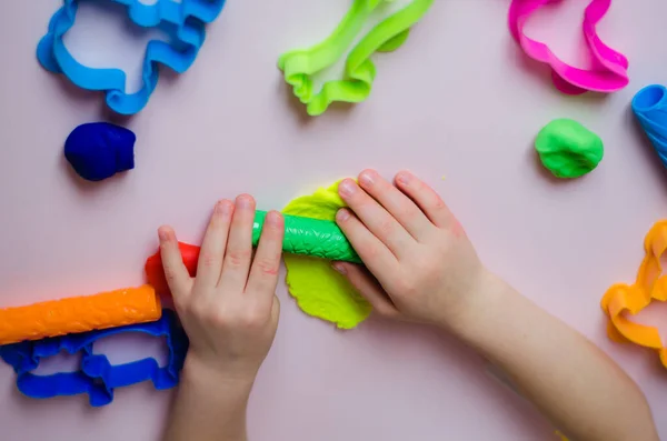 Çocuk elleri renkli kille oynuyor. Ev yapımı plastik. Kil kalıbı yapan kız. Ev yapımı kil. Çocuk oyun oynuyor ve oyun hamurundan yaratıyor. 