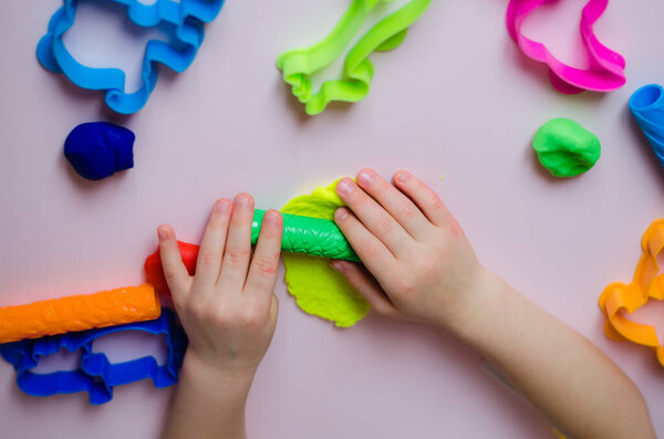 Child hands playing with colorful clay. Homemade plastiline. Girl molding modeling clay. Homemade clay. Child playing and creating from play dough. 
