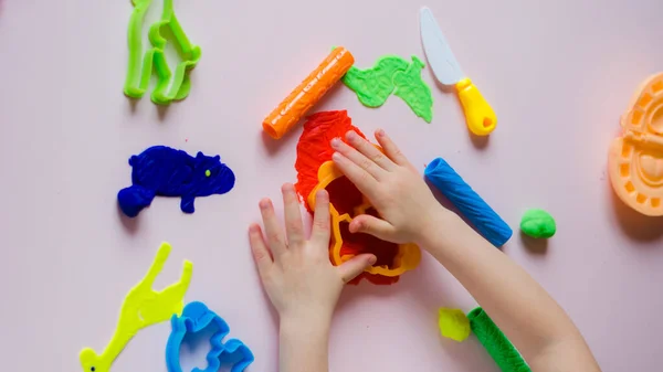 Çocuk elleri renkli kille oynuyor. Ev yapımı plastik. Kil kalıbı yapan kız. Ev yapımı kil. Çocuk oyun oynuyor ve oyun hamurundan yaratıyor. 