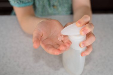 Küçük kız ellerine hijyen spreyi ya da alkol jeli sıkar. Çocuğun elindeki antiseptik temizleme jeli. Kapatın. Koronavirüs salgını sırasında hijyen..