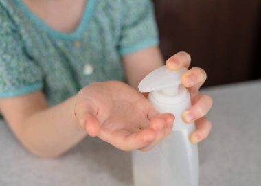 Küçük kız ellerine hijyen spreyi ya da alkol jeli sıkar. Çocuğun elindeki antiseptik temizleme jeli. Kapatın. Koronavirüs salgını sırasında hijyen..