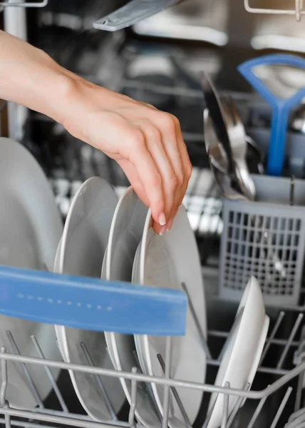 The woman puts dirty dishes in the dishwasher. Opening and closing the dishwasher. Open dishwasher with clean dishes. Close up, selective focus