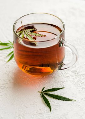 Bir fincan CBD çayı. Bir fincan marihuana ve beyaz arka planda taze yeşil yapraklı çay..