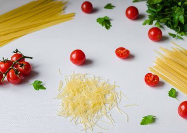 Pişmemiş makarna. Beyaz arka planda makarna pişirmek için malzemeli kiraz domatesleri. Yakın çekim