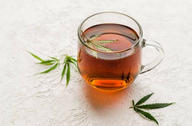 Bir fincan CBD çayı. Bir fincan marihuana ve beyaz arka planda taze yeşil yapraklı çay..