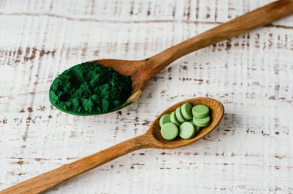 Spirulina powder and tablets in wooden spoon