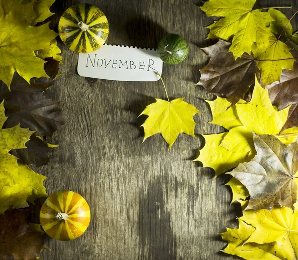 Hojas coloridas de otoño con calabazas sobre un fondo de madera . —  Fotos de Stock