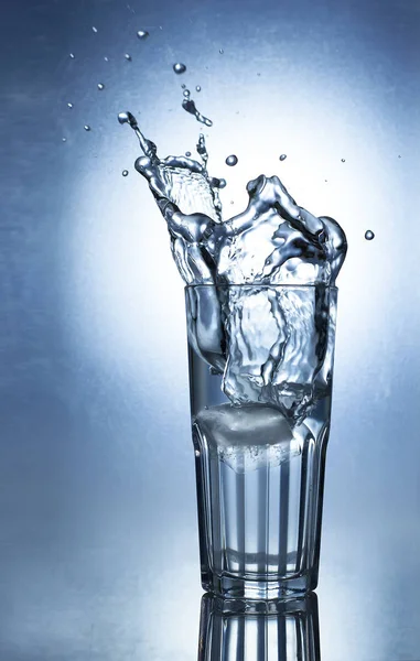 Splashing water of ice in a cool glass of water — Stock Photo, Image