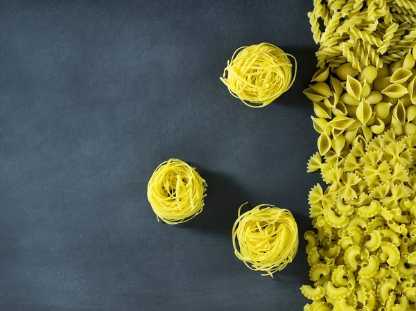 Diferentes tipos de pasta italiana seca sobre un fondo azul oscuro . — Foto de Stock