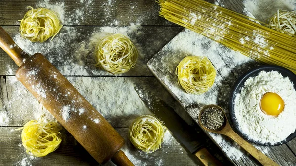İtalyan makarna, un ve rustik ahşap bir masa üzerinde çiğ yumurta.