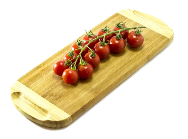 Tomates cereja maduros em uma tábua de corte em um fundo branco . — Fotografia de Stock