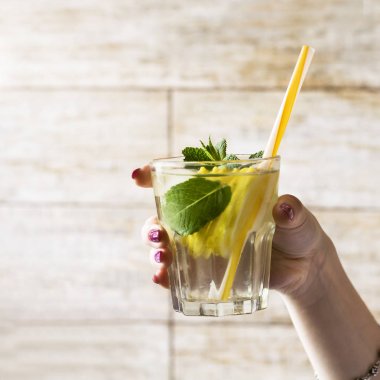 Detoks su bir limon ve taze nane bir kızın elini bırakır. Sağlıklı yaşam tarzı.