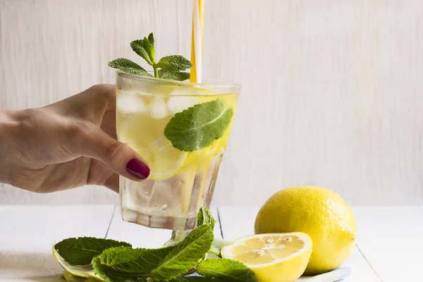 Склянка детоксикаційної води з лимоном і свіжим листя м'яти в руці дівчини. Здоровий спосіб життя . — стокове фото