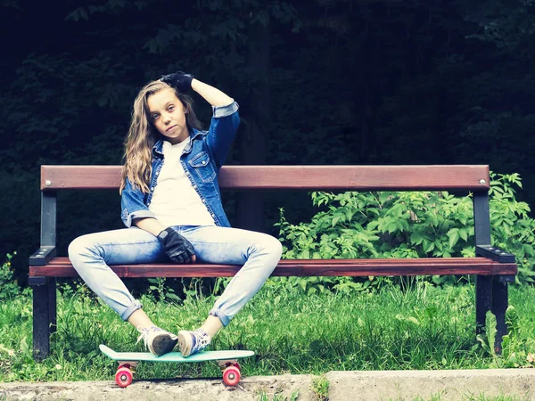 ジーンズのシャツ、バックパックとスケート ボード公園のベンチに座っている美しい金髪の十代の少女 — ストック写真