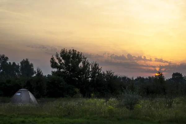 Beau lever de soleil dans un champ avec des nuages incroyables. Une tente. Voyages . — Photo