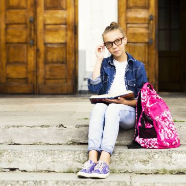 Sevimli sarışın kız kız öğrenci okul yakınındaki otururken bir kitap okuma. Eğitim.