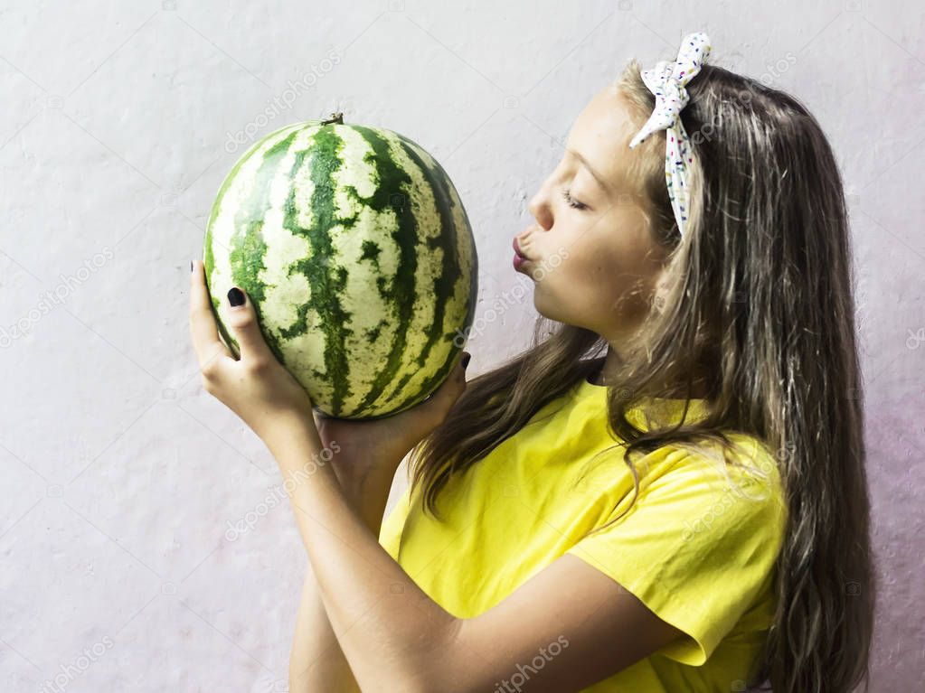 A cute girl holding a ripe watermelon.