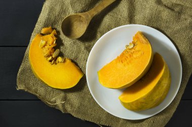 Olgun kabak tohumu ve bir tahta kaşık ile beyaz bir tabak içinde dilimlenmiş. Hasat. Sonbahar.