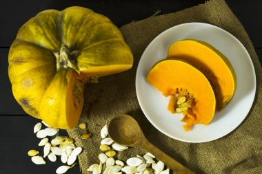 Olgun kabak tohumu ve bir tahta kaşık ile beyaz bir tabak içinde dilimlenmiş. Hasat. Sonbahar.