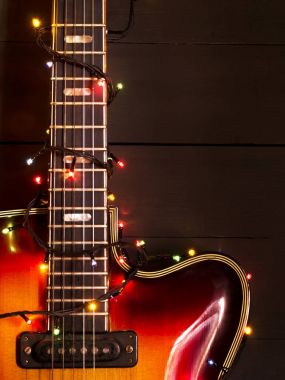 Eski elektro gitar ile karanlık bir arka plan üzerinde yanan bir çelenk. Tebrik, Noel, yeni yıl tebrik kartı. Kopya alanı.