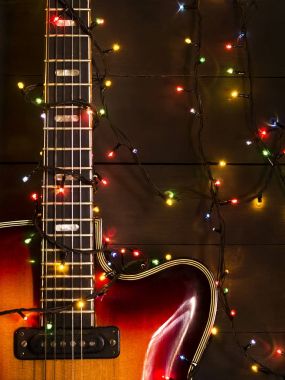 Eski elektro gitar ile karanlık bir arka plan üzerinde yanan bir çelenk. Tebrik, Noel, yeni yıl tebrik kartı. Kopya alanı.