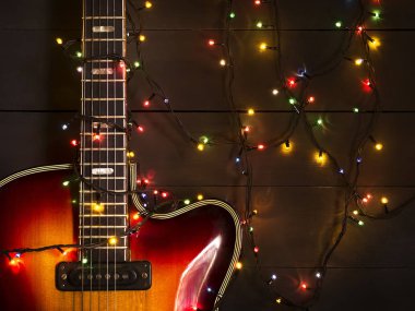 Eski elektro gitar ile karanlık bir arka plan üzerinde yanan bir çelenk. Tebrik, Noel, yeni yıl tebrik kartı. Kopya alanı.