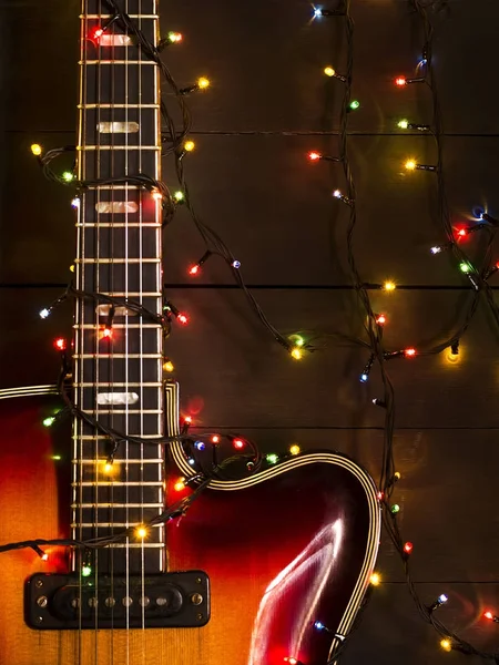 Vieille guitare électrique avec une guirlande éclairée sur un fond sombre. Salutations, Noël, carte de voeux du Nouvel An. Espace de copie . — Photo