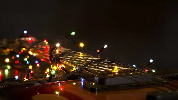 Παλιά ηλεκτρική κιθάρα με ένα φωτιζόμενο Γιρλάντα σε σκούρο φόντο. Χαιρετισμό, Χριστούγεννα, νέο έτος ευχετήρια κάρτα. Χώρο αντίγραφο. — Φωτογραφία Αρχείου