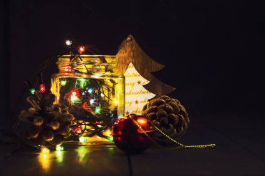 Bir cam kavanoz ve koyu ahşap arka plan üzerinde Noel süsleri parlak çelenk. Yeni yıl, yılbaşı kartpostal. Kopya alanı.