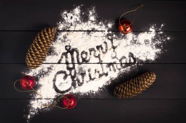 Kitabe mutlu Noeller, koyu ahşap arka plan üzerinde un ile yazılmış. Noel tebrik kartı.