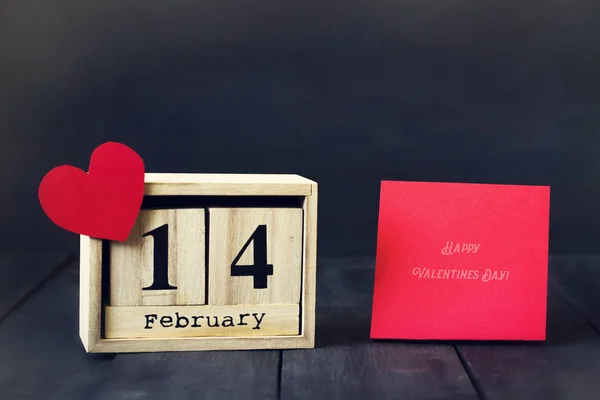 Houten kalender op de datum van 14 februari papier hart en cadeau. Op een donkere houten achtergrond met kopie ruimte. Valentijnsdag. — Stockfoto