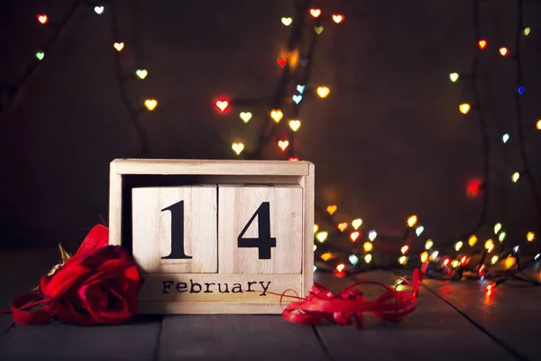 Calendario in legno dal 14 febbraio e una rosa rossa Su uno sfondo di legno scuro con spazio copia. San Valentino . — Foto Stock