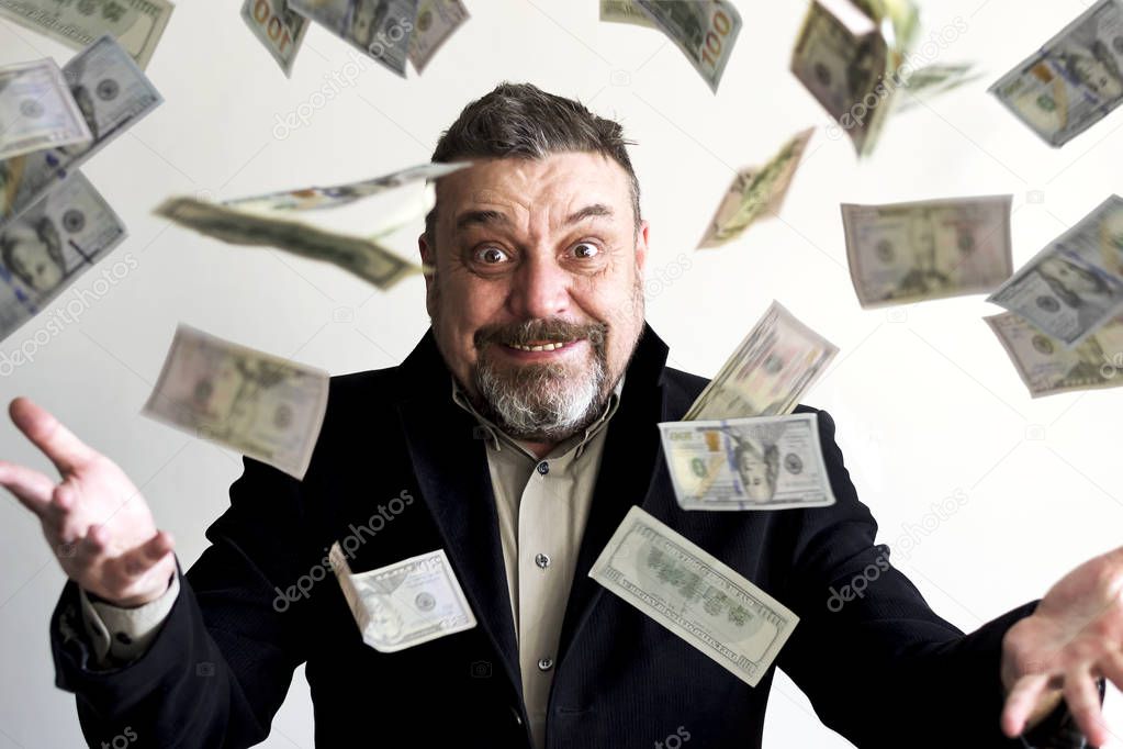 Happy bearded man in a suit, with dollar bills falling around him. Success. Finance.