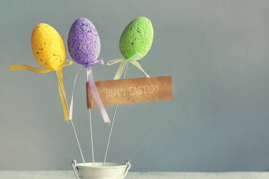 Çok renkli Paskalya yumurta küçük beyaz kova sopa üzerinde. Mutlu Paskalya yazıt. Kopya alanı.