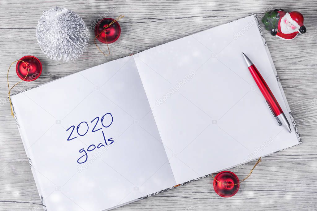 2020. Goals. Concept of ideas and goals for the new year. Notepad with festive decor on a wooden table. Copy space. Business.