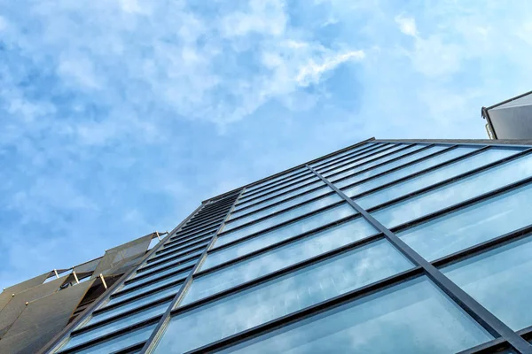 Modern mirror building on a background of cloudy sky. Bottom view Architecture.