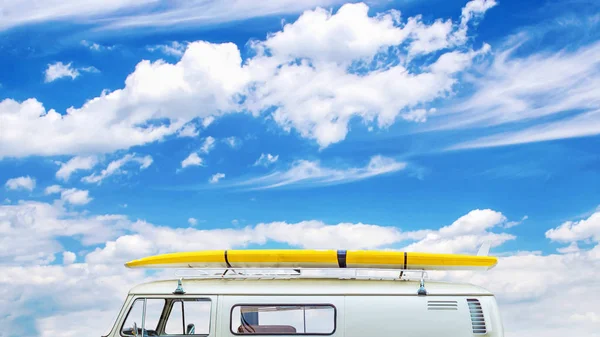 Old minibus with surfing on the trunk on a background of blue cloudy sky. Travel concept. summer holidays, hobbies. Copy space. Place for text. Travel.