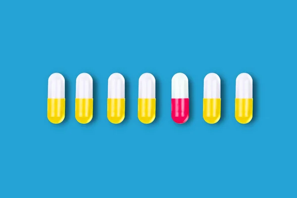 一颗红色药丸和许多黄色的蓝色背景 医疗背景 — 图库照片