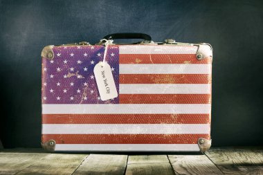 Tahta arka planda Amerikan bayrağı olan eski bavul..