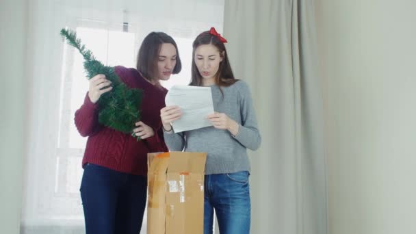 Two young girl preparing Christmas tree for decorations and having fun New year — Stock video