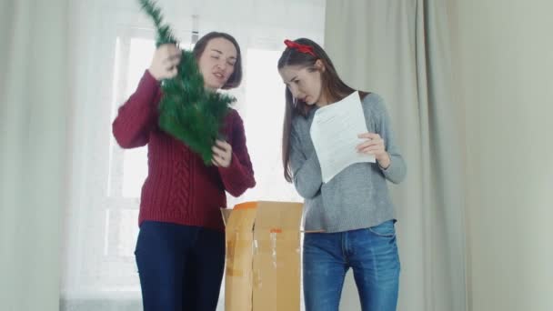 Two young girl preparing Christmas tree for decorations and having fun New year — ストック動画