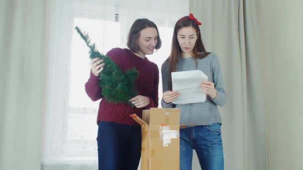 Two young girl preparing Christmas tree for decorations and having fun New year — Stock video